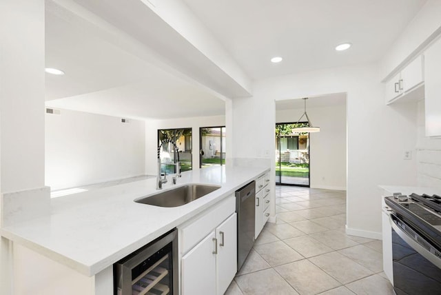 kitchen with sink, hanging light fixtures, beverage cooler, and white cabinets