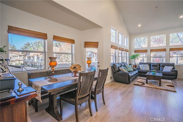 dining room featuring high vaulted ceiling and light hardwood / wood-style floors