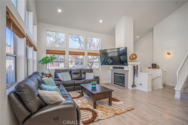 living room with a towering ceiling and light hardwood / wood-style flooring