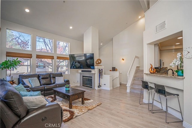 living room with sink, light hardwood / wood-style floors, and a high ceiling