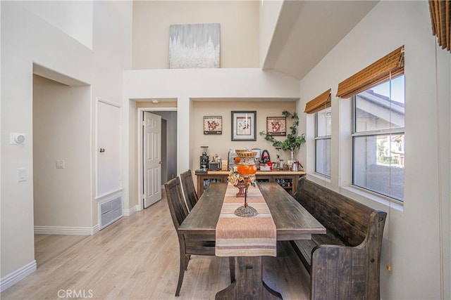 dining space with light hardwood / wood-style flooring and a high ceiling