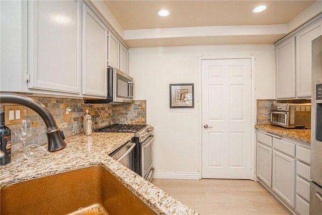 kitchen featuring sink, tasteful backsplash, light hardwood / wood-style flooring, stainless steel appliances, and light stone countertops