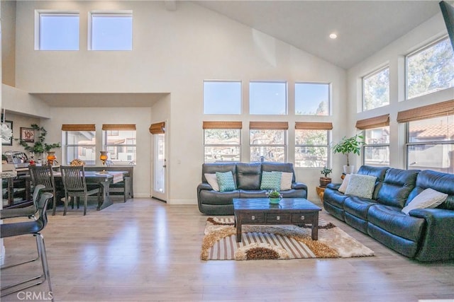 living room featuring high vaulted ceiling and light wood-type flooring