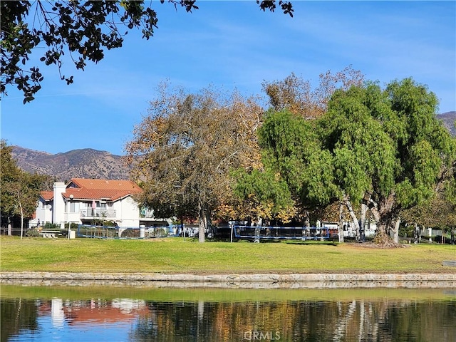 exterior space featuring a water and mountain view and a lawn