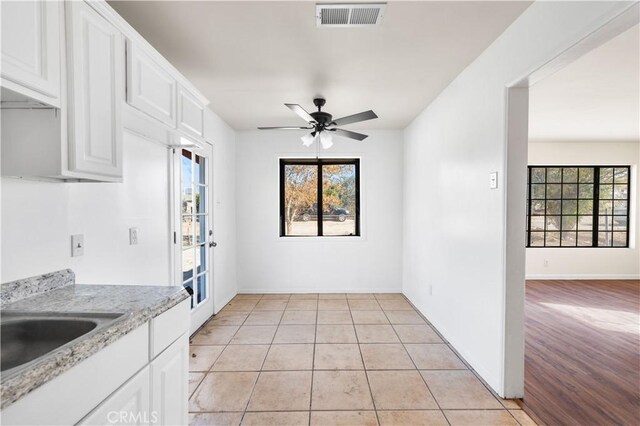 kitchen with white cabinets, light hardwood / wood-style floors, light stone counters, and ceiling fan