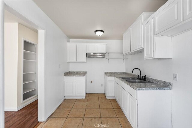 kitchen featuring light tile patterned floors, white cabinetry, and sink