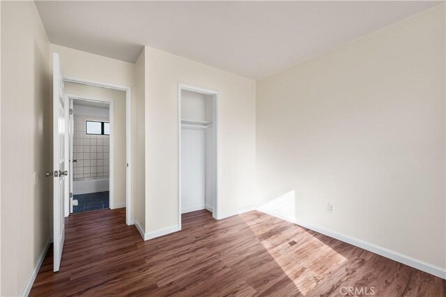 unfurnished bedroom with dark hardwood / wood-style flooring and a closet