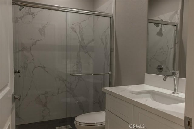 bathroom with vanity, a shower with shower door, and toilet