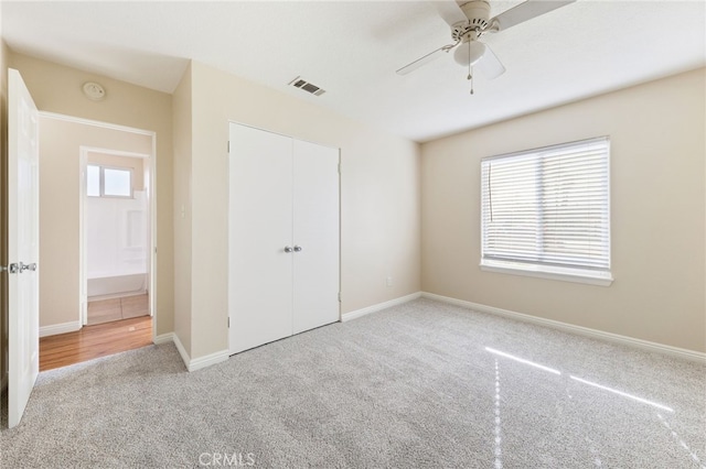 unfurnished bedroom featuring ceiling fan, a closet, and light colored carpet