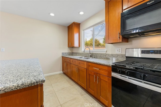 kitchen with light tile patterned flooring, sink, light stone counters, and stainless steel gas range oven