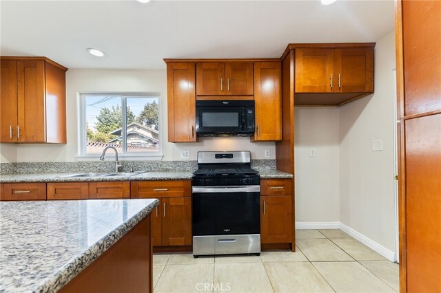 kitchen with light stone counters, sink, light tile patterned floors, and stainless steel range with gas stovetop