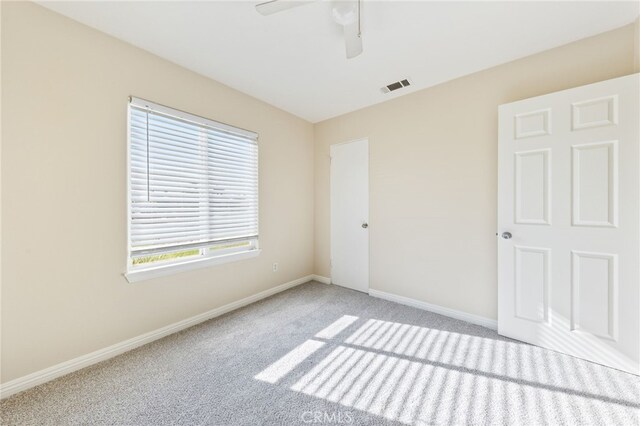 carpeted spare room featuring ceiling fan