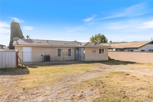 rear view of property featuring central AC unit and a lawn