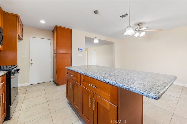 kitchen with ceiling fan, light stone countertops, range with gas cooktop, and a center island