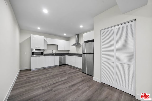 kitchen with white cabinets, wall chimney range hood, stainless steel appliances, and dark wood-type flooring