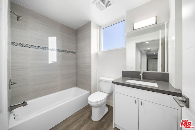 full bathroom featuring tiled shower / bath, hardwood / wood-style floors, vanity, and toilet