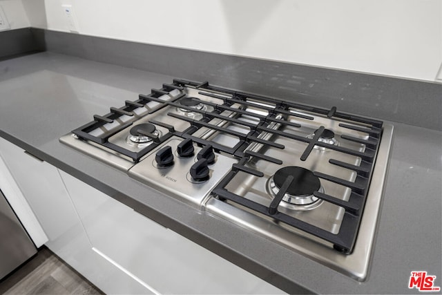 details featuring dark hardwood / wood-style flooring and stainless steel gas cooktop