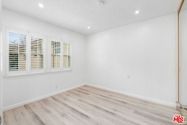 spare room featuring light hardwood / wood-style floors and a textured ceiling