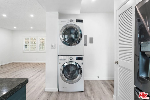 washroom with stacked washer and dryer, a textured ceiling, and light wood-type flooring