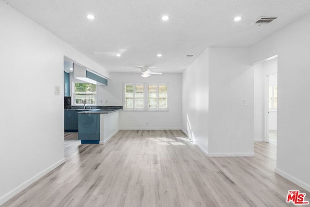 interior space featuring ceiling fan, light wood-type flooring, and a textured ceiling