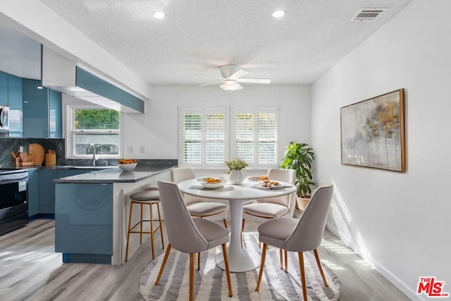 dining space with ceiling fan, light hardwood / wood-style flooring, a healthy amount of sunlight, and sink