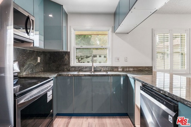 kitchen featuring blue cabinetry, stainless steel appliances, light hardwood / wood-style flooring, and sink