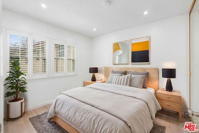 bedroom with light hardwood / wood-style floors and a textured ceiling