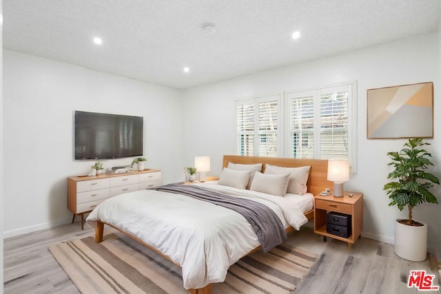 bedroom featuring light hardwood / wood-style flooring and a textured ceiling