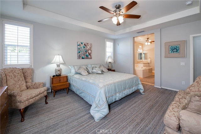 bedroom with ensuite bathroom, a raised ceiling, and ceiling fan