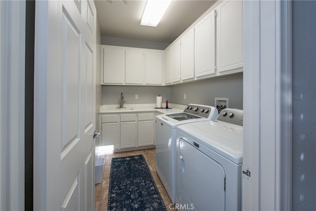 washroom with cabinets, washing machine and dryer, and sink