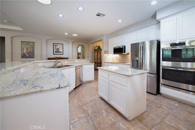 kitchen with a center island, sink, appliances with stainless steel finishes, tasteful backsplash, and light stone counters