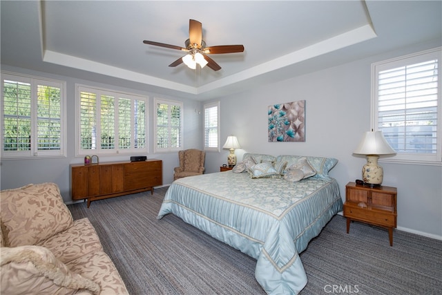 carpeted bedroom with a tray ceiling and ceiling fan