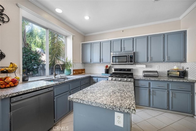 kitchen with decorative backsplash, ornamental molding, stainless steel appliances, sink, and a center island