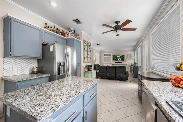 kitchen with stainless steel fridge with ice dispenser, a center island, light stone counters, and ornamental molding