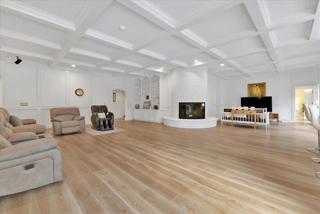 living room featuring a brick fireplace, built in shelves, and beamed ceiling