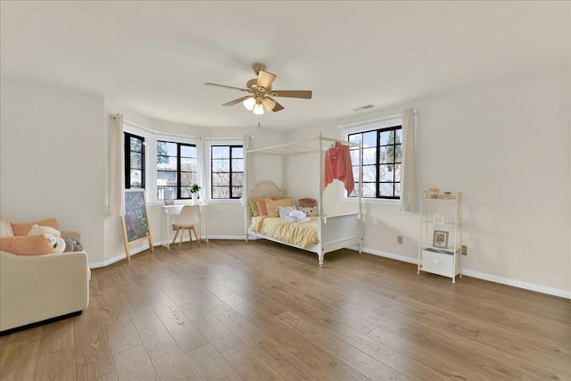 unfurnished bedroom with ceiling fan, multiple windows, and wood-type flooring