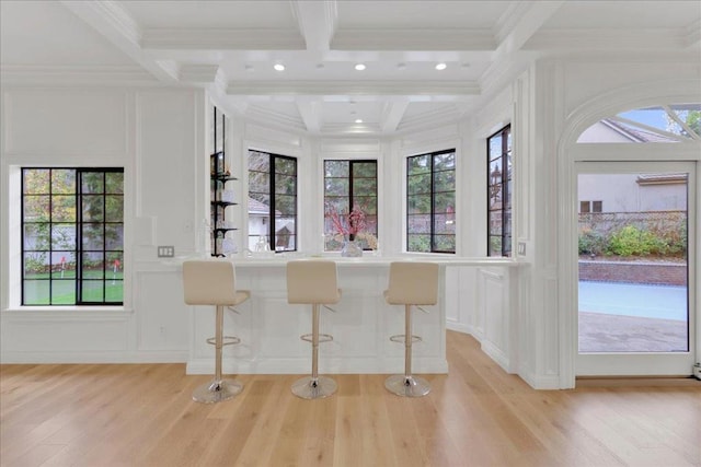 bar featuring coffered ceiling, ornamental molding, light hardwood / wood-style flooring, and beamed ceiling