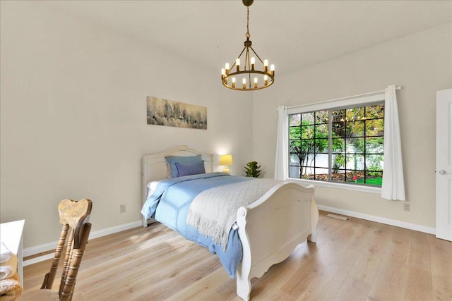 bedroom with light hardwood / wood-style floors and a chandelier