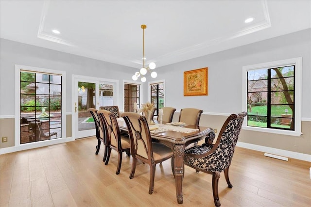 dining space featuring light hardwood / wood-style floors, a raised ceiling, and a notable chandelier