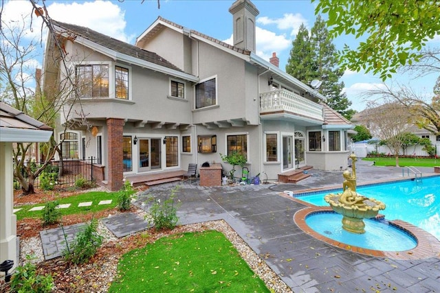 back of house featuring a balcony, a fenced in pool, and a patio