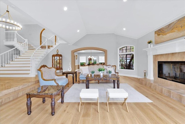 living room featuring light wood-type flooring, lofted ceiling, a notable chandelier, and a fireplace