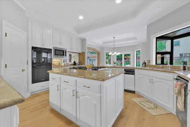 kitchen featuring kitchen peninsula, white cabinets, a raised ceiling, and decorative light fixtures