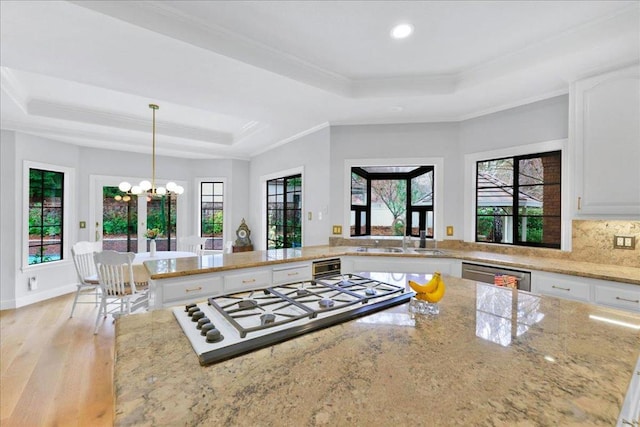 kitchen featuring light stone counters, a tray ceiling, white cabinetry, and pendant lighting