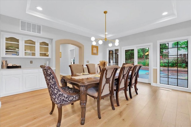 dining space with a tray ceiling and light hardwood / wood-style floors