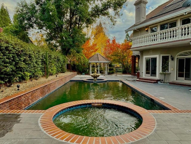 view of pool with an in ground hot tub, a gazebo, and a patio