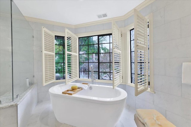 bathroom with a tub to relax in, tile walls, and crown molding