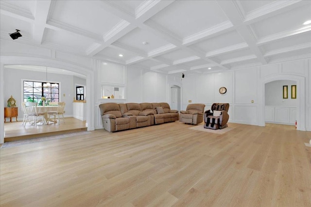 living room featuring beam ceiling, light wood-type flooring, coffered ceiling, and ornamental molding