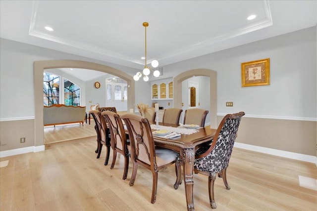 dining room with a tray ceiling and light hardwood / wood-style flooring