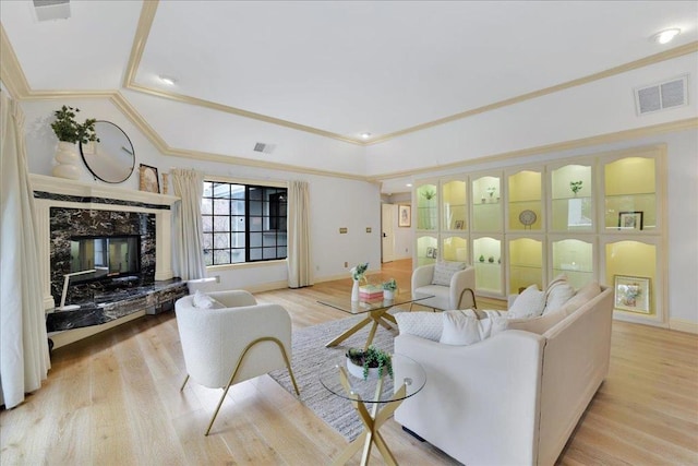 living room with a high end fireplace, ornamental molding, and light hardwood / wood-style flooring