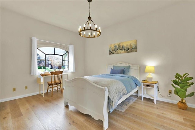 bedroom with light hardwood / wood-style floors and an inviting chandelier